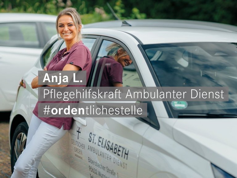 Pflegehilfskraft des Ambulanten Dienstes steht vor ihrem Auto laechelt freundlich in die Kamera 