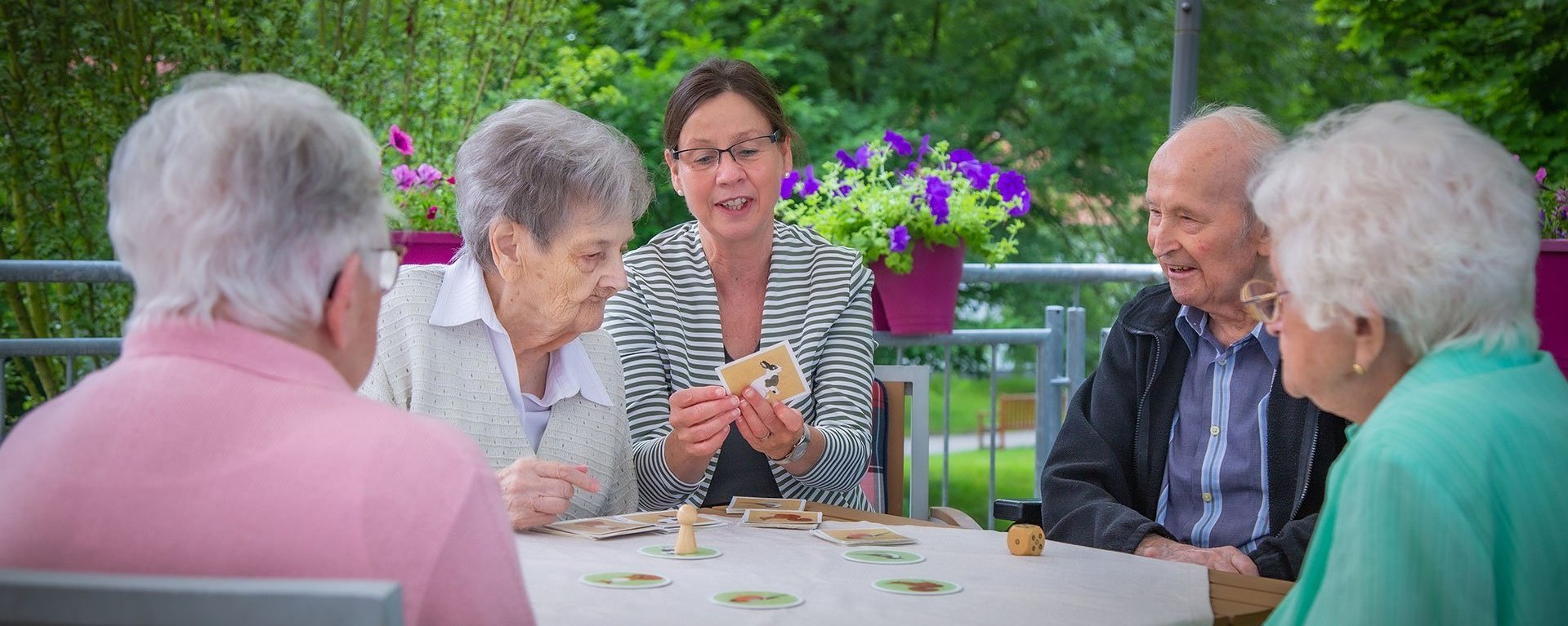 Eine Gruppe von fünf Personen sitzt um einem Tisch und spielt Karten